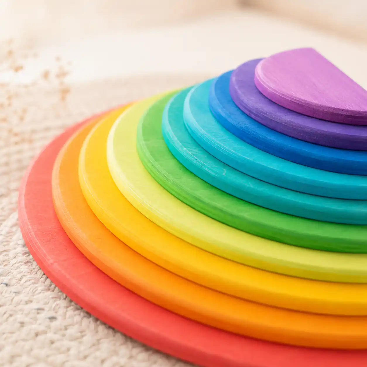 Close-up of wooden rainbow semicircles showing soft color wash and visible wood grain in classic Waldorf style