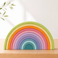 12-piece wooden rainbow stacker in soft Macaron pastel colors arranged in nested arches on a cream background