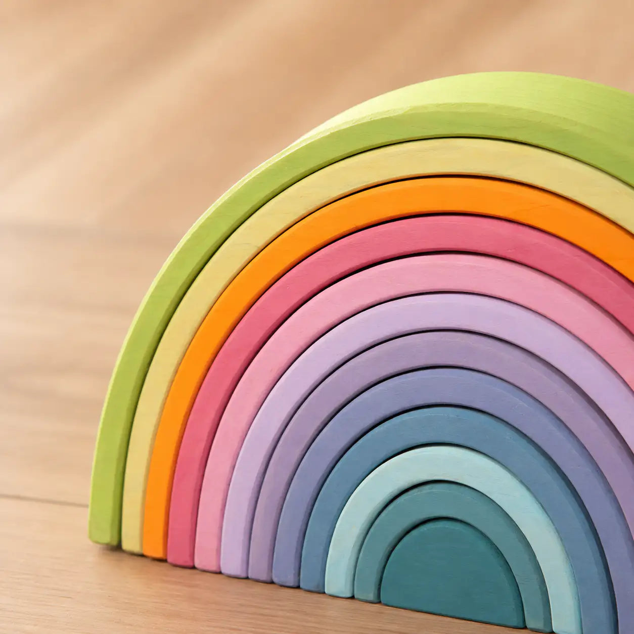 Close-up of the smooth matte finish and sanded wood grain on a Macaron pastel rainbow stacker arch piece