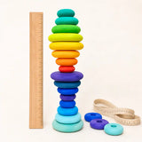 Wooden rainbow stacking discs tower beside a ruler and tape measure showing scale and size