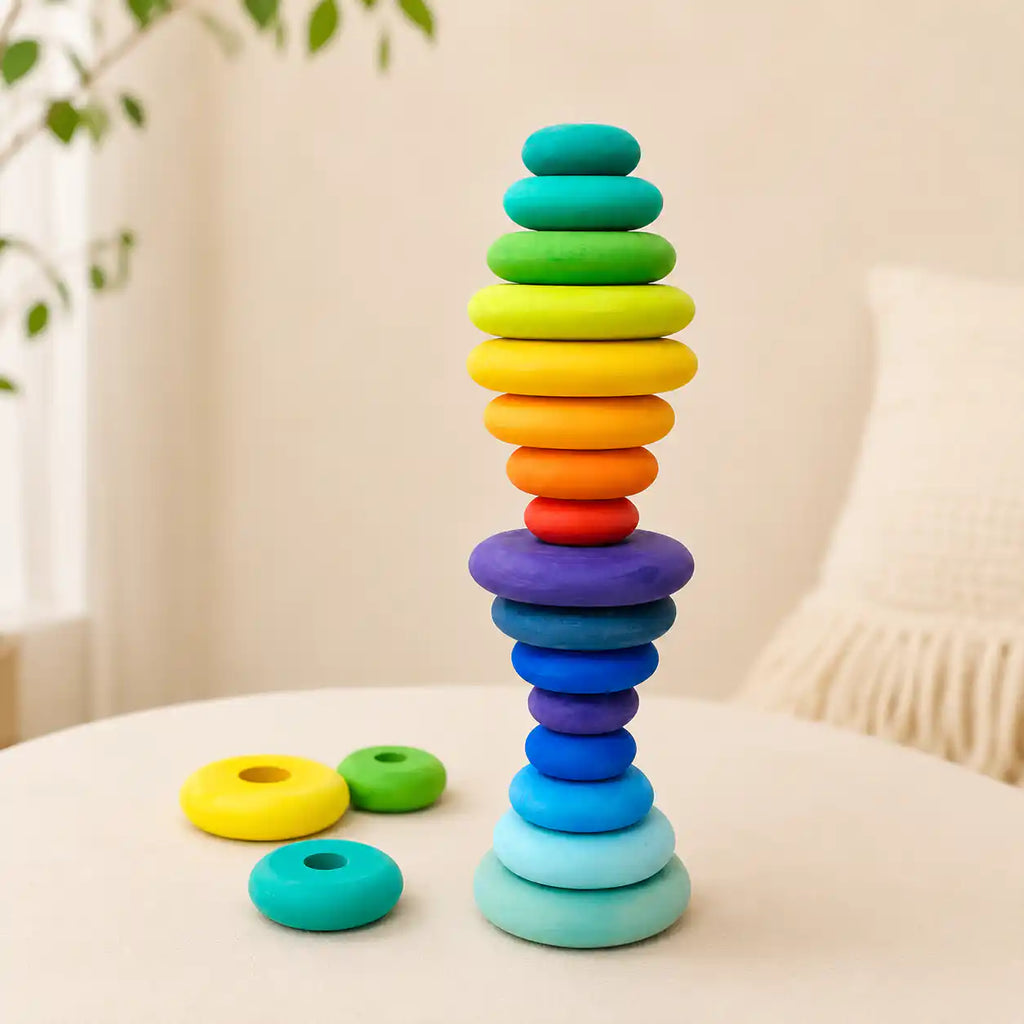 Wooden rainbow stacking discs tower with extra graduated discs resting beside it