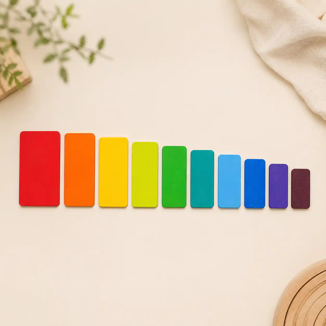 Wooden rainbow stacking tablets laid out in a line showing graduated sizes and rainbow color order