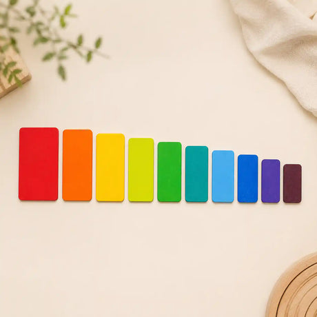 Wooden rainbow stacking tablets laid out in a line showing graduated sizes and rainbow color order