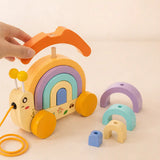 Wooden snail stacker with pastel arches restacked into a tall balance tower beside it for open-ended play