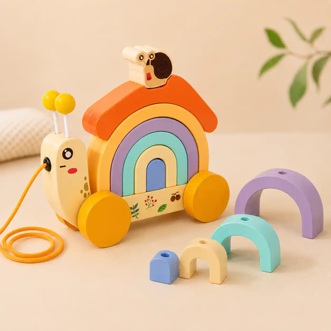 Hand demonstrating how the orange roof lifts off the wooden snail rainbow stacker to reveal the nesting arches